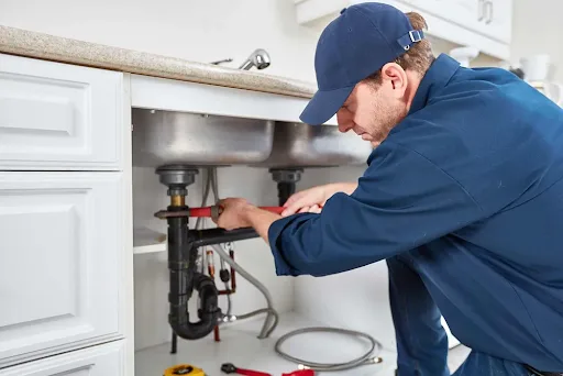 Plumber repairing pipes under a sink during a hidden water leak inspection in Columbia, SC